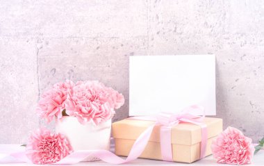 Anneler Günü hediye kutusu fotoğrafçılık dileği - pembe kurdele kutulu güzel karanfiller açık gri arka plan masasına izole edilmiş, kapatın, kopyalayın, taklit edin
