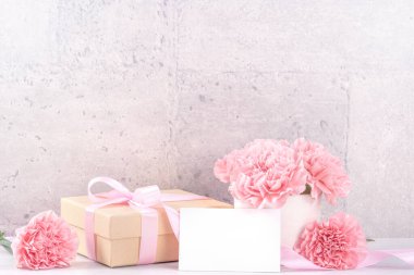Anneler Günü hediye kutusu fotoğrafçılık dileği - pembe kurdele kutulu güzel karanfiller açık gri arka plan masasına izole edilmiş, kapatın, kopyalayın, taklit edin
