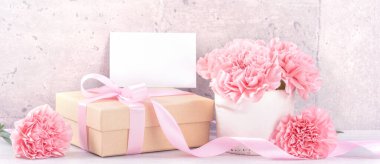 Anneler Günü hediye kutusu fotoğrafçılık dileği - pembe kurdele kutulu güzel karanfiller açık gri arka plan masasına izole edilmiş, kapatın, kopyalayın, taklit edin