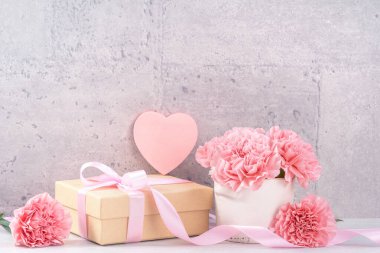 Anneler Günü hediye kutusu fotoğrafçılık dileği - pembe kurdele kutulu güzel karanfiller açık gri arka plan masasına izole edilmiş, kapatın, kopyalayın, taklit edin