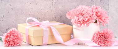 Anneler Günü hediye kutusu fotoğrafçılık dileği - pembe kurdele kutulu güzel karanfiller açık gri arka plan masasına izole edilmiş, kapatın, kopyalayın, taklit edin