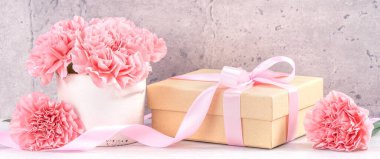 Anneler Günü hediye kutusu fotoğrafçılık dileği - pembe kurdele kutulu güzel karanfiller açık gri arka plan masasına izole edilmiş, kapatın, kopyalayın, taklit edin