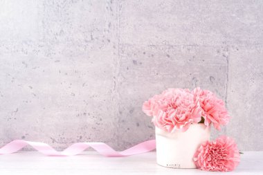 Anneler Günü hediye kutusu fotoğrafçılık dileği - pembe kurdele kutulu güzel karanfiller açık gri arka plan masasına izole edilmiş, kapatın, kopyalayın, taklit edin