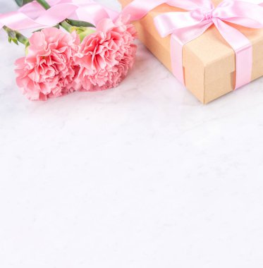 Anneler günü el yapımı hediye kutusu fikri, bebek pembe kurdeleli güzel karanfiller modern mermer masaya izole edilmiş, kapatın, kopyalayın, taklit edin