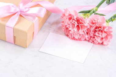 Anneler günü el yapımı hediye kutusu fikri, bebek pembe kurdeleli güzel karanfiller modern mermer masaya izole edilmiş, kapatın, kopyalayın, taklit edin