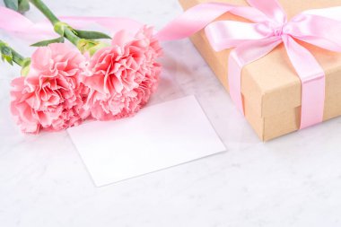 Anneler günü el yapımı hediye kutusu fikri, bebek pembe kurdeleli güzel karanfiller modern mermer masaya izole edilmiş, kapatın, kopyalayın, taklit edin