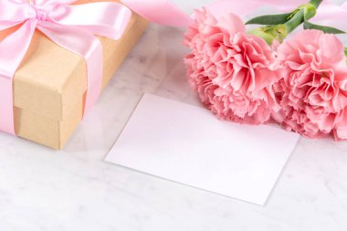 Anneler günü el yapımı hediye kutusu fikri, bebek pembe kurdeleli güzel karanfiller modern mermer masaya izole edilmiş, kapatın, kopyalayın, taklit edin