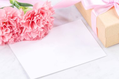 Anneler günü el yapımı hediye kutusu fikri, bebek pembe kurdeleli güzel karanfiller modern mermer masaya izole edilmiş, kapatın, kopyalayın, taklit edin