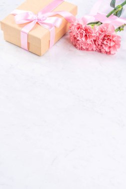 Anneler günü el yapımı hediye kutusu fikri, bebek pembe kurdeleli güzel karanfiller modern mermer masaya izole edilmiş, kapatın, kopyalayın, taklit edin