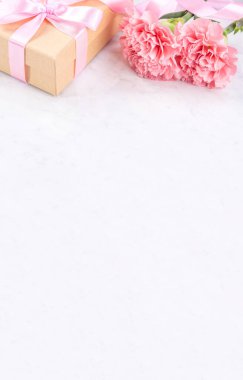 Anneler günü el yapımı hediye kutusu fikri, bebek pembe kurdeleli güzel karanfiller modern mermer masaya izole edilmiş, kapatın, kopyalayın, taklit edin