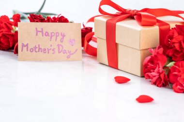 El yapımı giftbox fotoğrafçılık - modern mermer masasında izole kırmızı şerit yay kutusuyla güzel çiçek açan karanfil dilek Mayıs Anneler günü yakın çekim, uzay kopyalayın, yukarı alay