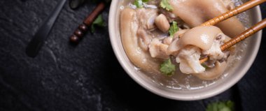 Üstte görünüm, yakın çekim, kopya alanı, Tayvan Asya ayırt edici sokak gıda, bej Fildişi krem-beyaz renkli kase koyu Shale arduvaz masada izole fıstık domuz knuckle çorba