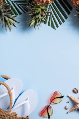 Yaz meyvesi tasarımı konsepti. Deniz kabukları, şapka, ananas ve mavi arka planda palmiye yapraklarıyla tatil gezilerinin en üst manzarası..