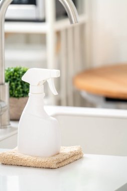 Modern mutfakta tezgah masasının yüzeyini silmek için lavabonun yanında temizlik malzemesi spreyi şişesi ve bez konsepti..