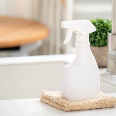 Modern mutfakta tezgah masasının yüzeyini silmek için lavabonun yanında temizlik malzemesi spreyi şişesi ve bez konsepti..