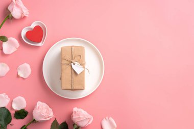Pembe gül çiçekli Anneler Günü tasarım konsepti ve pembe masa arkasında paketlenmiş Kraft hediye kutusu..