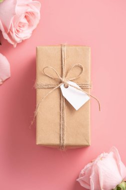 Pembe gül çiçekli Anneler Günü tasarım konsepti ve pembe masa arkasında paketlenmiş Kraft hediye kutusu..
