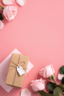 Pembe gül çiçekli Anneler Günü tasarım konsepti ve pembe masa arkasında paketlenmiş Kraft hediye kutusu..