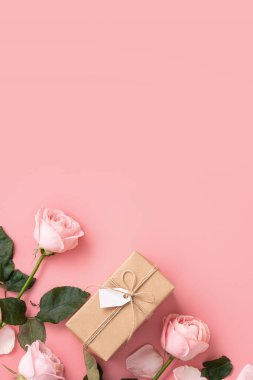 Pembe gül çiçekli Anneler Günü tasarım konsepti ve pembe masa arkasında paketlenmiş Kraft hediye kutusu..