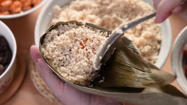 Herstellung von Zongzi-Essen - Zubereiten und Einwickeln chinesischer Reisknödel zu Hause für das Duanwu Drachenbootfest, Lebensstil.