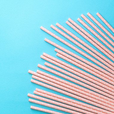 Mavi masa arka planında, biyolojik olarak çözünebilen, benekli, pembe kamış seti. Dünya Günü için çevre koruma kavramı..