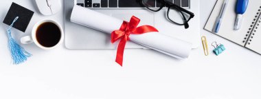 Çevrimiçi öğrenme ve uzaktan mezuniyet töreni tasarım konsepti. Beyaz masa arkasında akademik başlık, diploma ve dizüstü bilgisayar..
