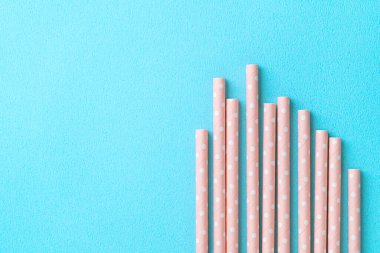 Mavi masa arka planında, biyolojik olarak çözünebilen, benekli, pembe kamış seti. Dünya Günü için çevre koruma kavramı..