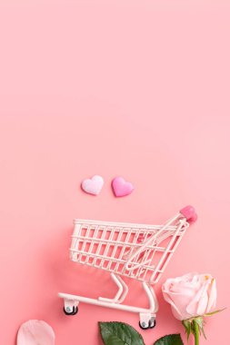 Anneler Günü alışveriş tasarımı konsepti pembe gül çiçeği ve el arabası arka planda.