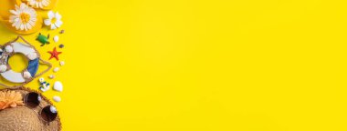 Yaz sahili tasarımı konsepti. Deniz kabukları, şapka, sarı arka planda terlik ile tatil seyahatinin en üst görüntüsü.