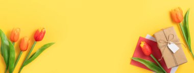 Anneler günü konsepti. Parlak sarı masa arkaplanında lale buketi olan bayram hediyesi tasarımı.