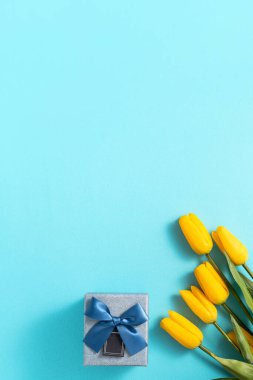 Anneler günü konsepti. Parlak mavi masa arkaplanındaki lale çiçeğini karşılama töreninin üst görünüm tasarımı.