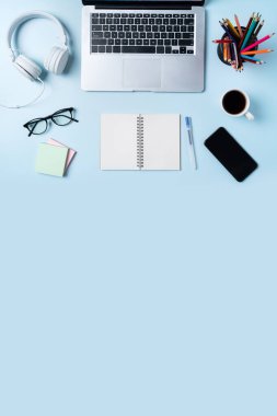 Çevrimiçi öğrenim tasarımı. Tabletli, kulaklıklı ve mavi masa arkaplanlı öğrenci tablosunun üst görünümü.