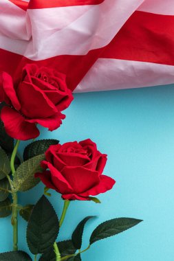 ABD 'nin Bağımsızlık Günü ya da Anma Günü kavramı. Kırmızı gül ile mavi masa üzerinde ulusal bayrak.