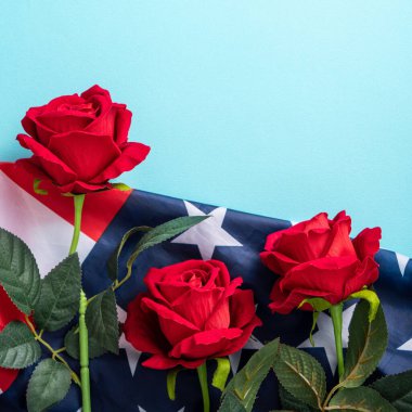 ABD 'nin Bağımsızlık Günü ya da Anma Günü kavramı. Kırmızı gül ile mavi masa üzerinde ulusal bayrak.