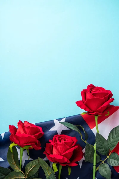 Concept of U.S Independence day or Memorial day. National flag over blue table background with red rose.