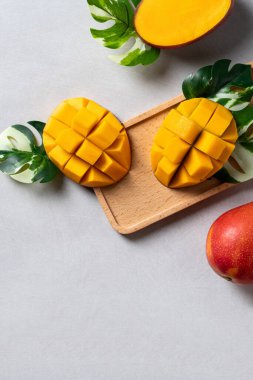 Mango arka plan tasarımı konsepti. Gri masa yaprakları ile kesilmiş taze mango desenli üst manzara.