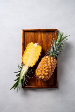 Koyu mavi arka planda tropikal yapraklı taze kesilmiş ananas manzarası.