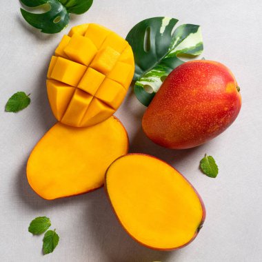 Mango arka plan tasarımı konsepti. Gri masa yaprakları ile kesilmiş taze mango desenli üst manzara.