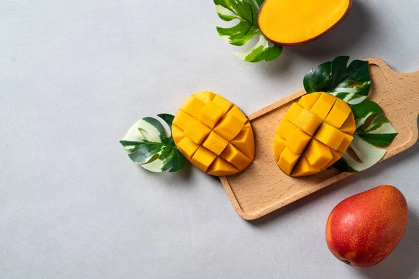Mango arka plan tasarımı konsepti. Gri masa yaprakları ile kesilmiş taze mango desenli üst manzara.