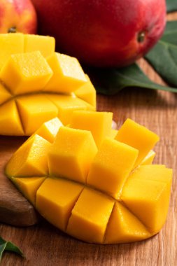 Mango. Taze olgun mango meyvelerini koyu ahşap masa zemininde yeşil yapraklarla kaplayın..