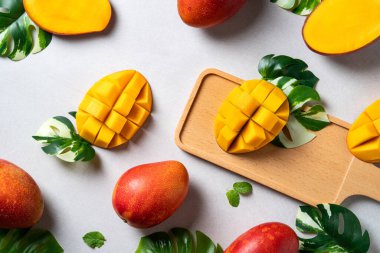 Mango arka plan tasarımı konsepti. Gri masa yaprakları ile kesilmiş taze mango desenli üst manzara.