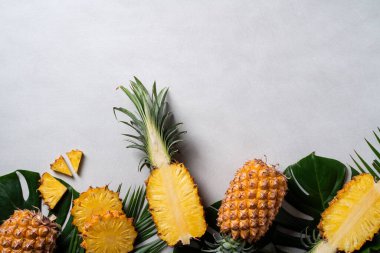 Koyu mavi arka planda tropikal yapraklı taze kesilmiş ananas manzarası.