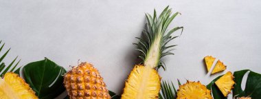 Koyu mavi arka planda tropikal yapraklı taze kesilmiş ananas manzarası.