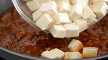 Cooking Mapo tofu. Homemade stir-frying tofu with hot spicy sauce in a pot at home.