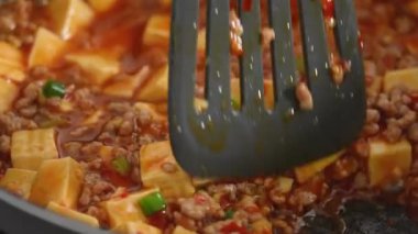 Cooking Mapo tofu. Homemade stir-frying tofu with hot spicy sauce in a pot at home.