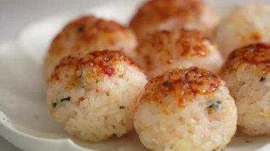 Brush sweet soy yaki sauce and mayonnaise on small round rice ball in takoyaki style at home. 