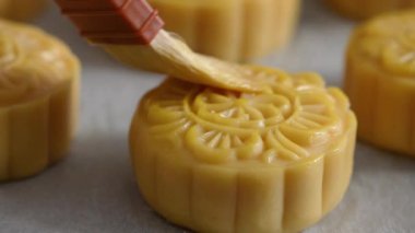 Brushing egg liquid on moon cake pastry surface before baking for Mid-Autumn Festival food concept.