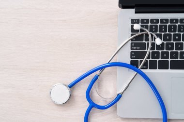 Doctor diagnoses design concept - stethoscope on computer keyboard with medical record clipboard on white working table.