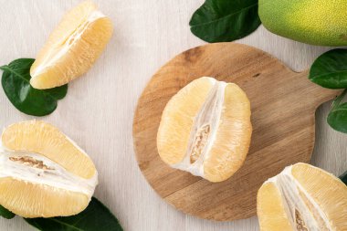 Güz ortası meyve festivali için parlak ahşap masa arkasında soyulmuş taze pomelo manzarası.