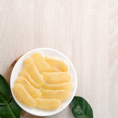 Güz ortası meyve festivali için parlak ahşap masa arkasında soyulmuş taze pomelo manzarası.